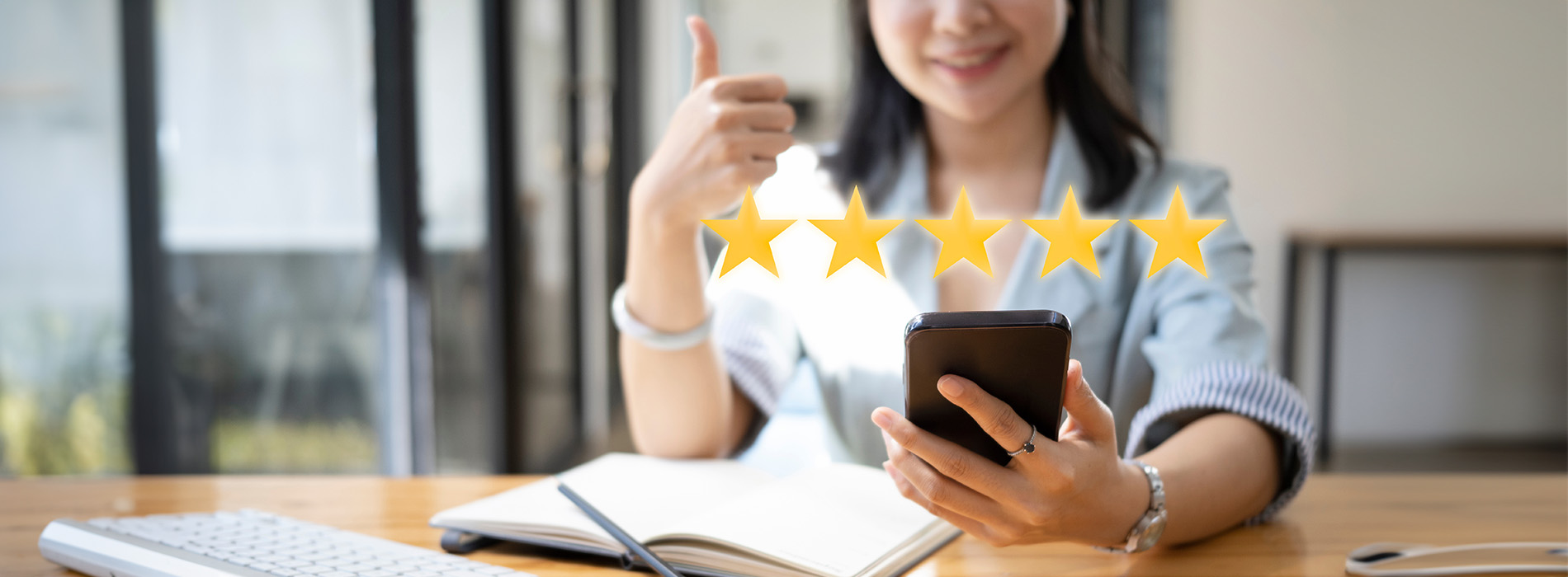 The image shows a hand holding a tablet with a star rating graphic on the screen, indicating high customer satisfaction or approval.